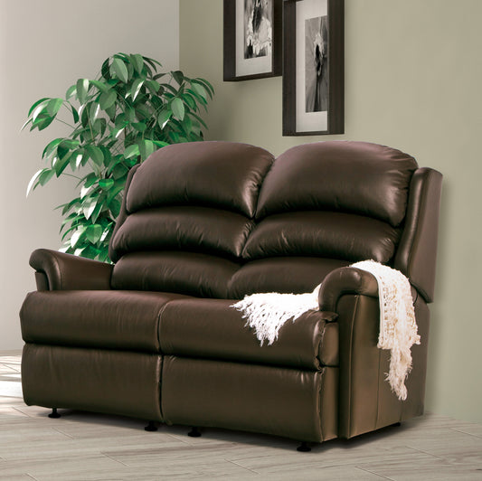 Brown leather sofa with a white blanket in a room with a plant and framed pictures.